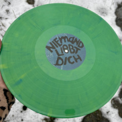 Ene grün marmorierte Vinyl mit einem blauen Eti8kett, auf dem steht „niemand liebt dich“, wird von einer Hand gehalten.