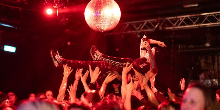 Diversity Dive #5 - Team Scheisse & 24/7 Diva Heaven 1 Eine Flinta wird von Händen getragen unter der Disco-Kugel