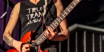 Patsy Stone spielt voll Eifer mit einer roten Gitarre auf einer Bühne