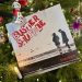 Das Cover in schwarz weiß mit roter Schrift "Buster Shuffle - Together", zeigt die Silhouette von zwei Menschen, die auf ein Gewässer mit Schiffen schauen. Im Hintergrund ist ein beleuchteter Tannenbaum zu sehen mit Weihnachtsschmuck.