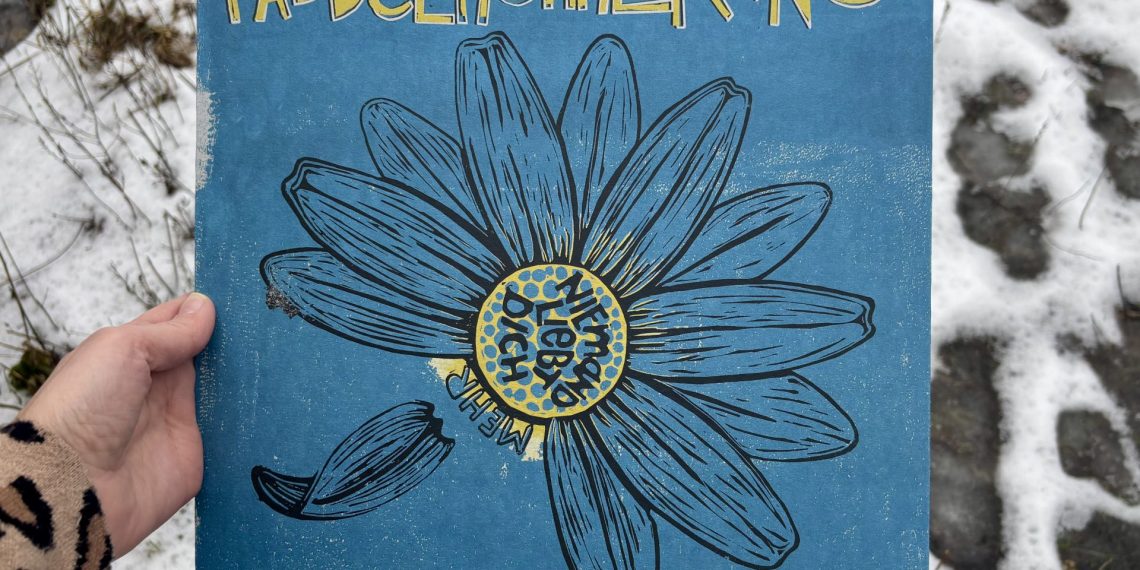 Ein Albumcover mit eines Linolschnitts eines Gänseblümchens auf blauem Grund. Ein paar Blütenblätter fehlen, eines löst sich gerade vom Blütenstandsboden. Die inneren, gelben Röhrenblüten sind angedeutet in gelb auf den blauen Untergrund gedruckt. Der Schriftzug paddelnohnekanu ist gelb mit weißer Umrandung prominent am oberen Rand platziert. Daraus ergibt sich eine Farbpalette von blau, gelb, weiß und schwarz für das Cover. Eine Hand hält das Album vor einem Hintergrund aus Schnee mit Fußspuren.