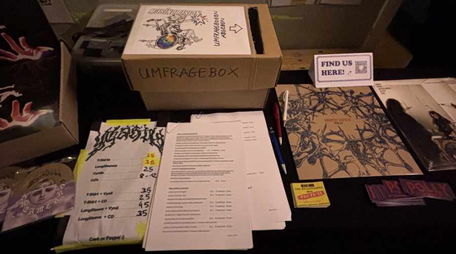 MusInclusion #34 - Band Workshop und so viele weitere coole Dinge! 4 Eine Umfragebox steht auf einem Merchtisch, davor liegen Umfragebögen.