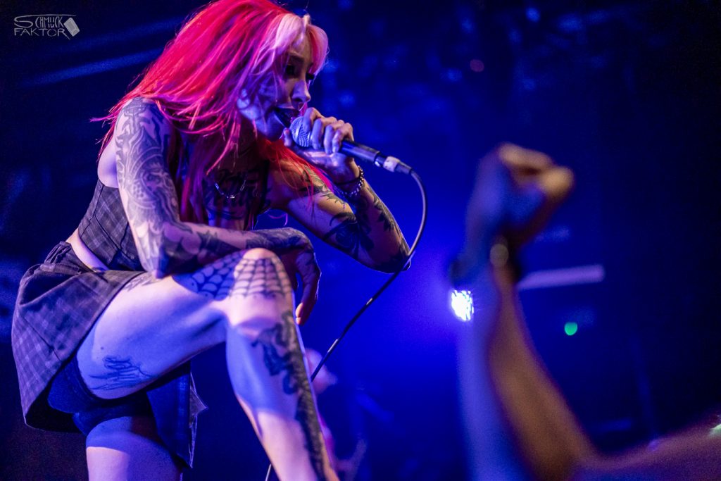 Interview mit Gero / Female Fronted is not a Genre Festival 2026 18 Eine Sängerin mit roten Haaren und Tatoos sing im blauen Bühnen-Licht, im Publikum wird eine Faust gereckt