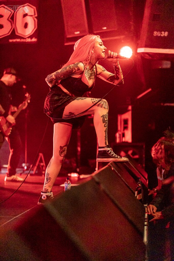 Interview mit Gero / Female Fronted is not a Genre Festival 2026 16 Eine Sängerin steht in rotes Licht getauscht mit einem Fuss auf den Monitoren und singt ins Mikrofon
