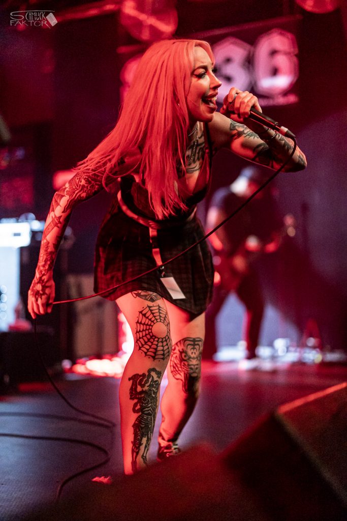 Interview mit Gero / Female Fronted is not a Genre Festival 2026 12 Eine Sängerin mit roten Haaren und Tattoo singt in ein Mikrofon.